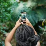 Woman photographing plants to illustrate patience and growth in SEO
